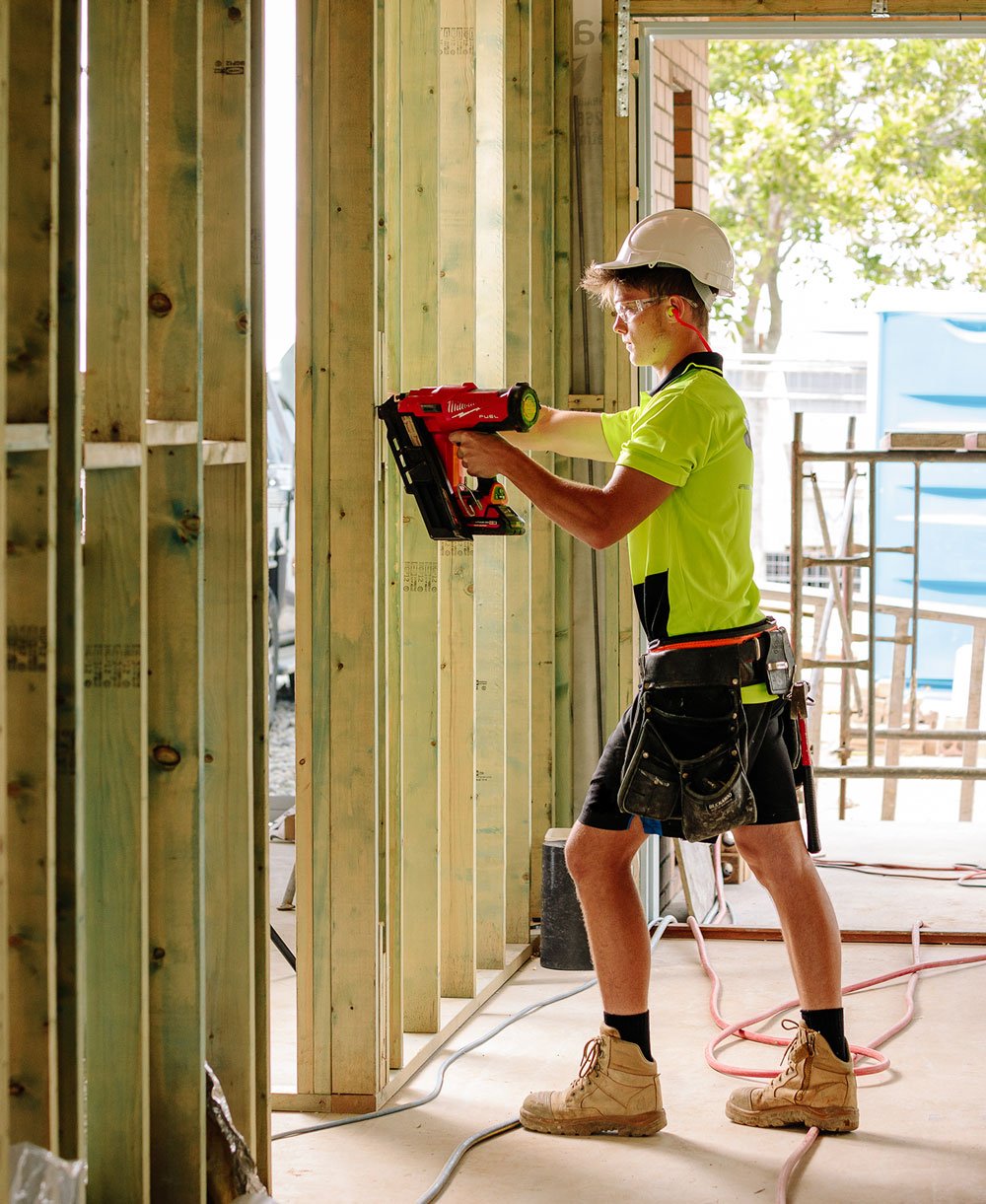 Carpentry apprentice using framing gun on frame Carpentry apprentice using framing gun on frame