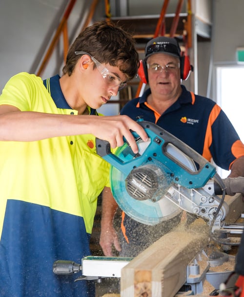 Certificate II in Construction Pathways student using drop saw while trainer supervises Certificate II in Construction Pathways student using drop saw while trainer supervises