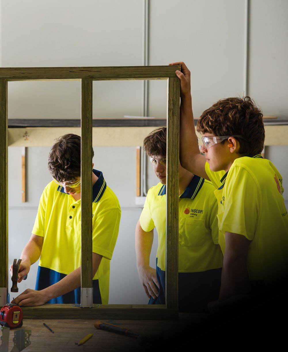 Certificate II in Construction Pathways student using hammer while peers watch on Certificate II in Construction Pathways student using hammer while peers watch on